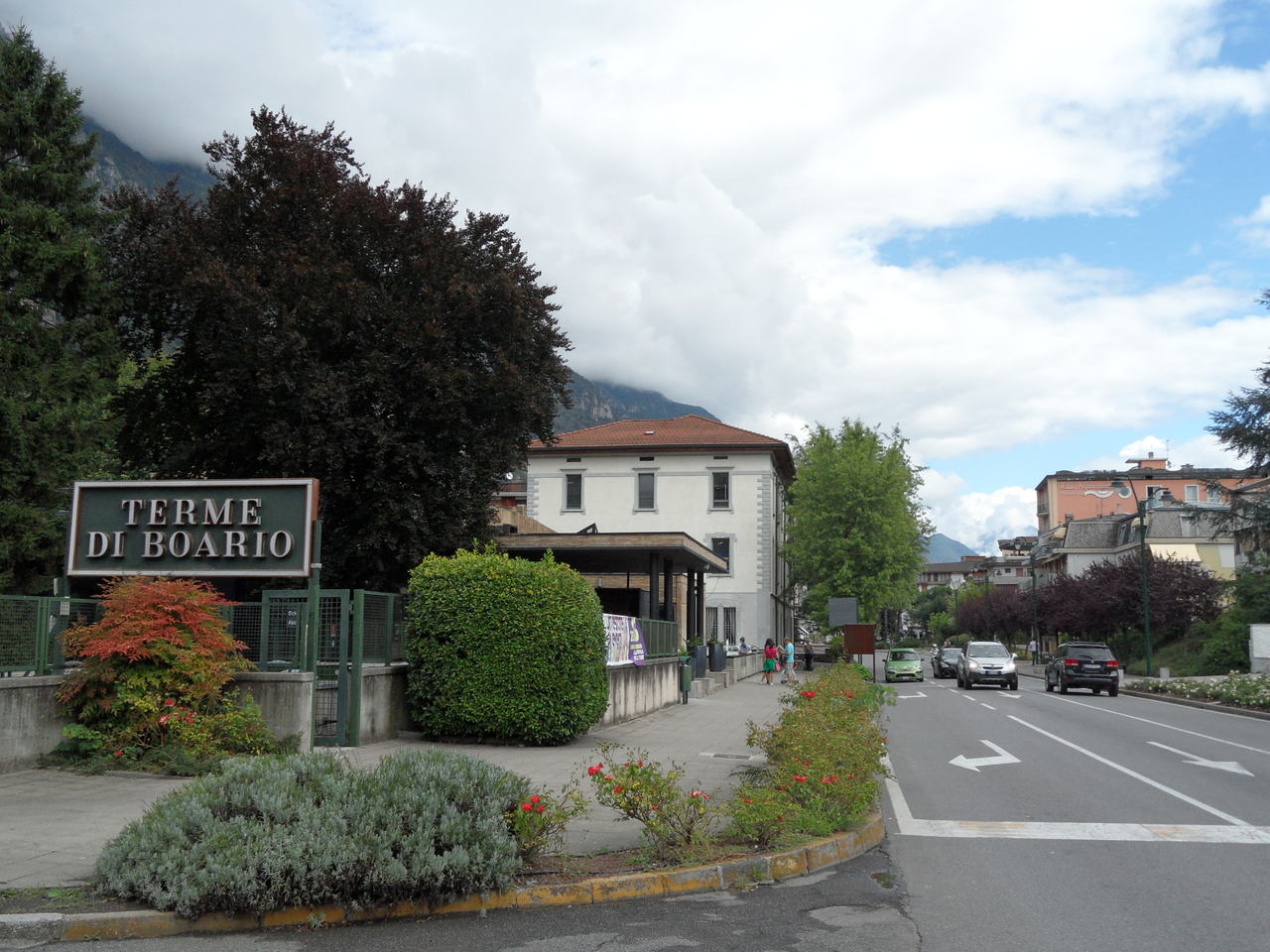 L'ingresso delle Terme di Boario, con l'edificio storico dietro le siepi del parco e la strada in primo piano.