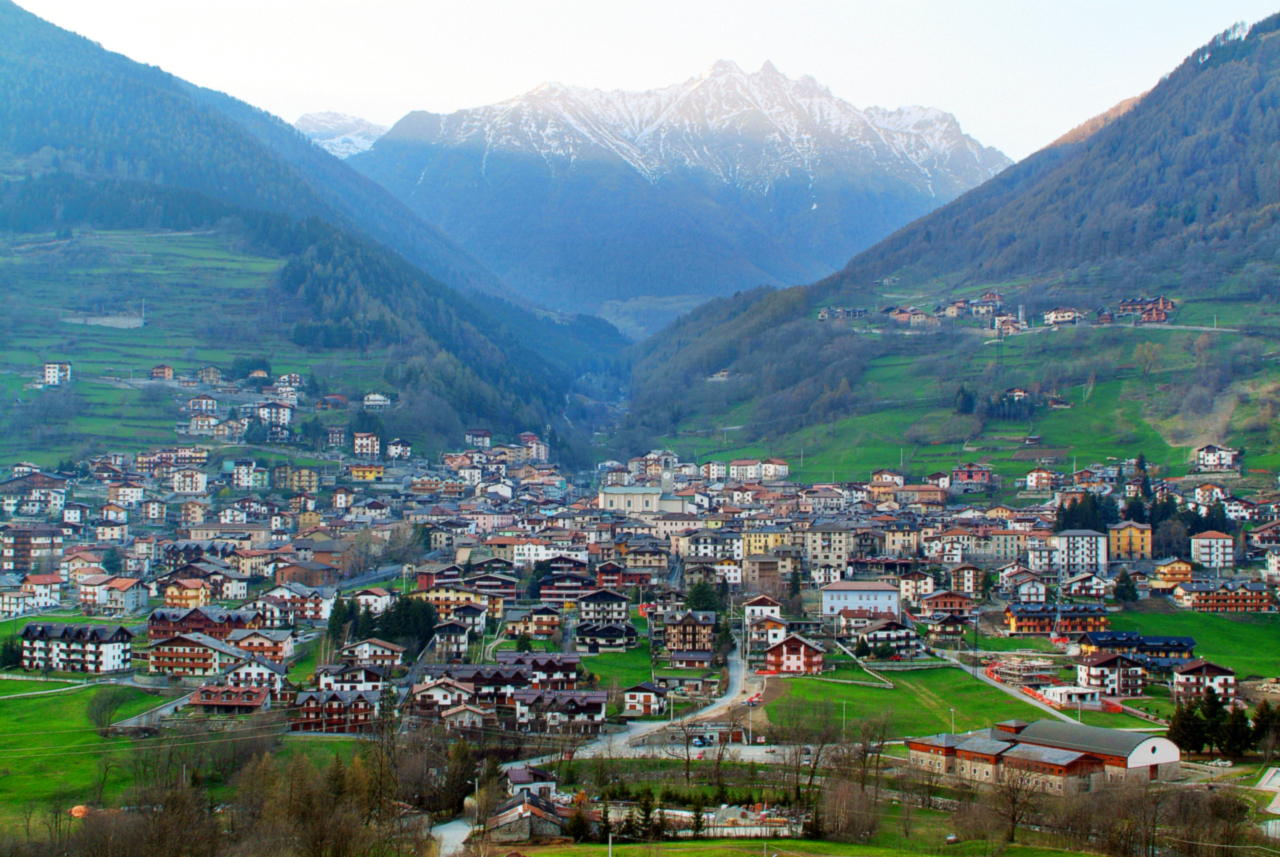 L'abitato di Vezza d'Oglio disteso sul fondovalle fra prati e boschi, con le cime innevate che chiudono la testata della valle.